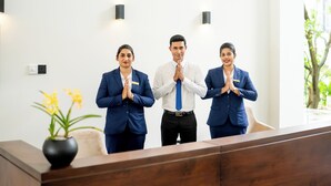 Three individuals in business attire standing at a reception desk in a modern hotel lobby. - Waters Edge Hotel (Battaramulla)