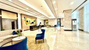 Un hall d’entrée moderne avec un canapé, des fauteuils, un comptoir d’accueil et un mur décoratif.