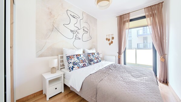 A bedroom with a bed, nightstand, and a wall with a line drawing.