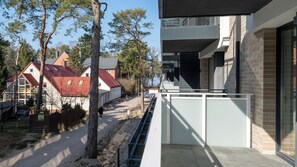 Un bâtiment moderne doté d’un balcon donnant sur une rue bordée de maisons et d’arbres.