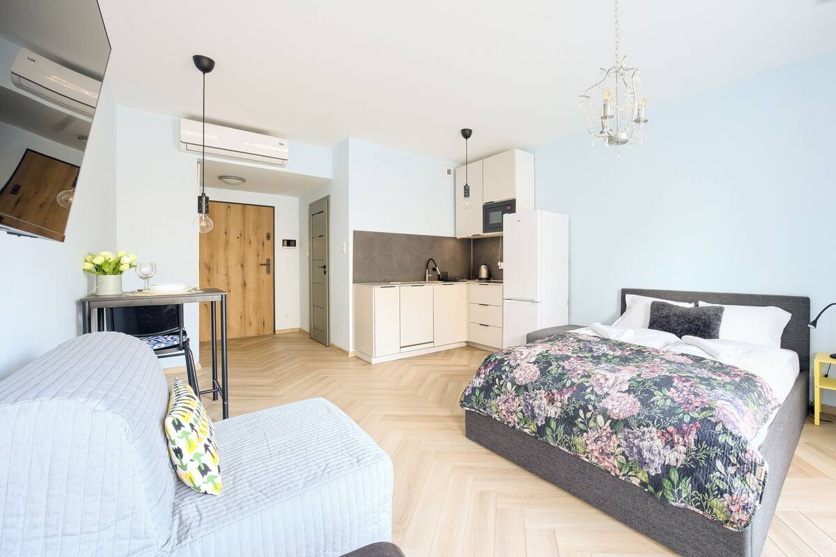 A modern bedroom with a large bed, a small kitchenette, and a separate sitting area.
