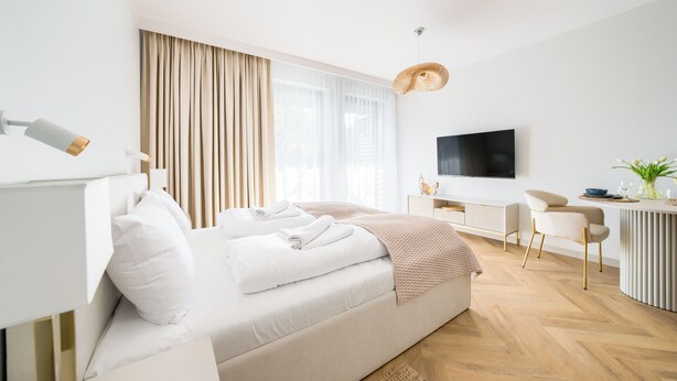 Een moderne hotelkamer met een bed, bureau, televisie en zithoek.