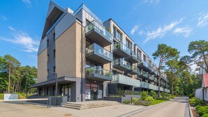 Een modern meerlaags gebouw met balkons, een hekpoort en een aangelegde tuin.