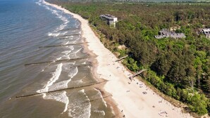 Luchtbeeld van een strand met een hotel, heldere lucht en een bebost gebied.