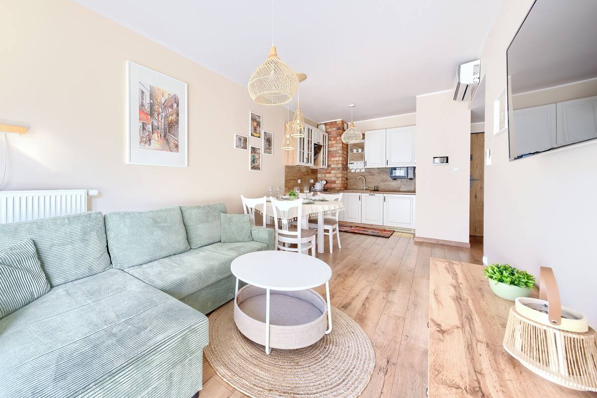 A modern living room with a sectional sofa, a round coffee table, and a dining area with a white table and chairs.
