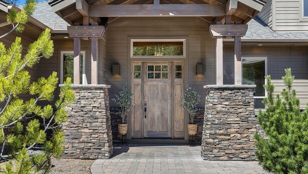 A house with a stone facade, a wooden front door, and a covered entryway.