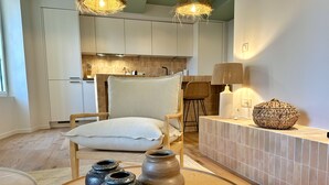 Ein modernes Wohnzimmer mit einem runden Holztisch, drei Keramiktöpfen, einem gewebten Korb und einer Lampe auf einem weißen Konsolentisch.