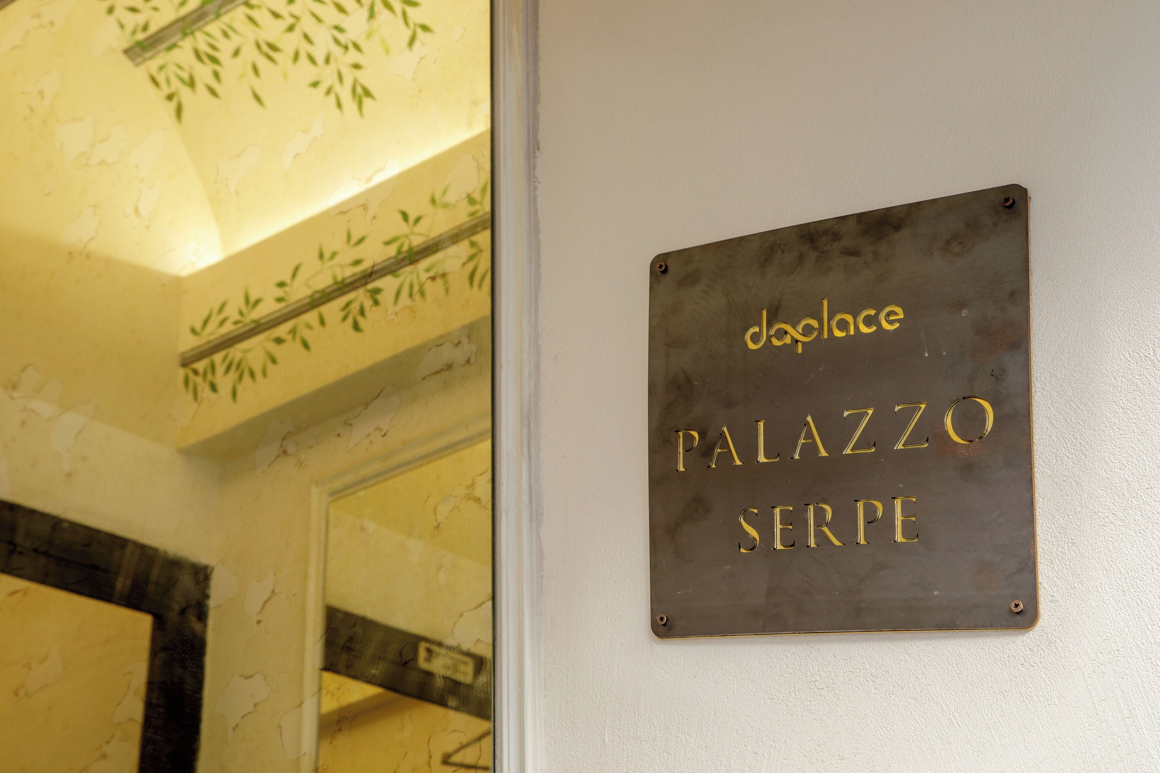 A sign with the text "doglace PALAZZO SERPE" on a wall.
