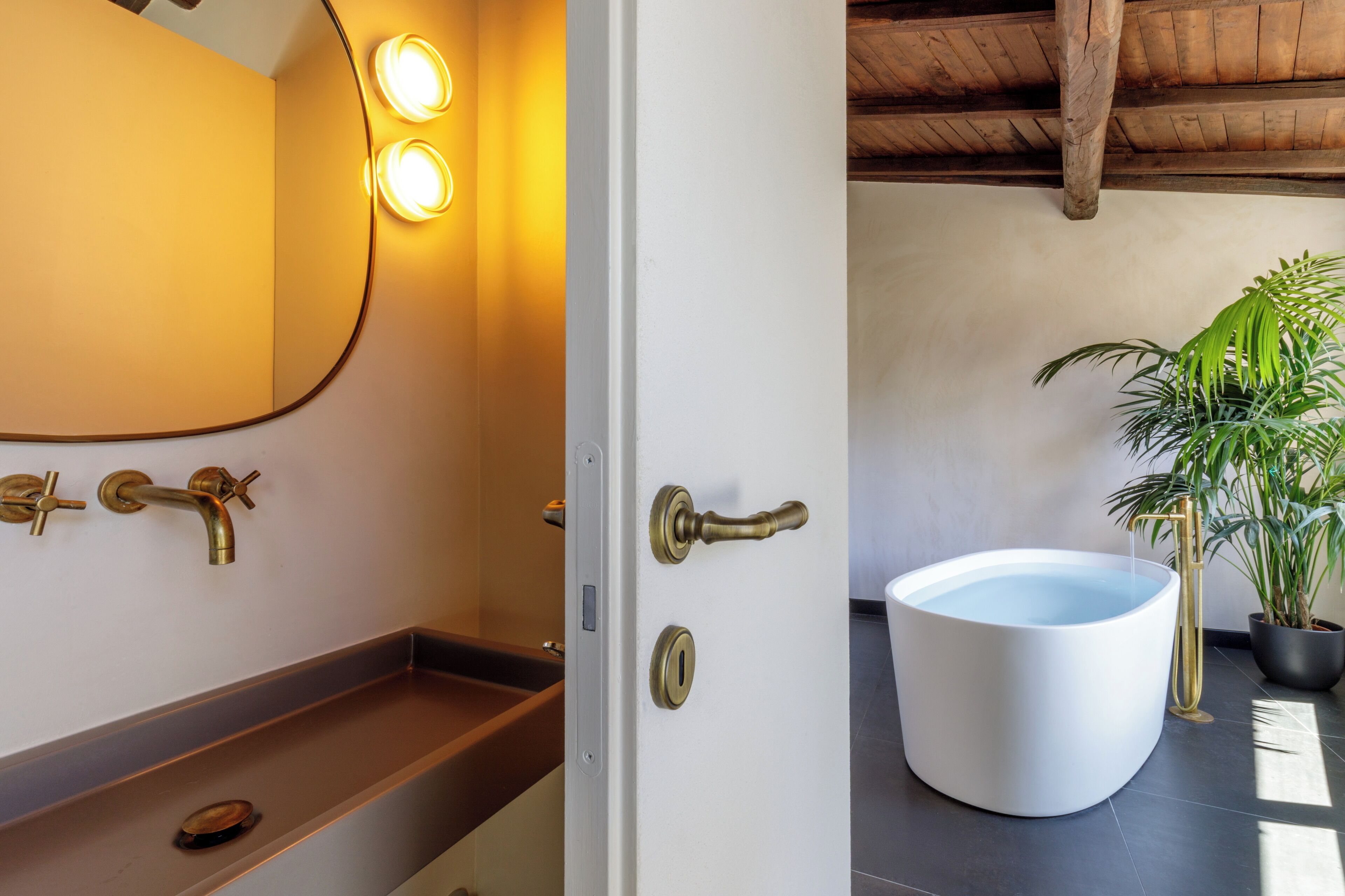 Un baño con una bañera blanca, un tocador de madera y un espejo con tres luces.