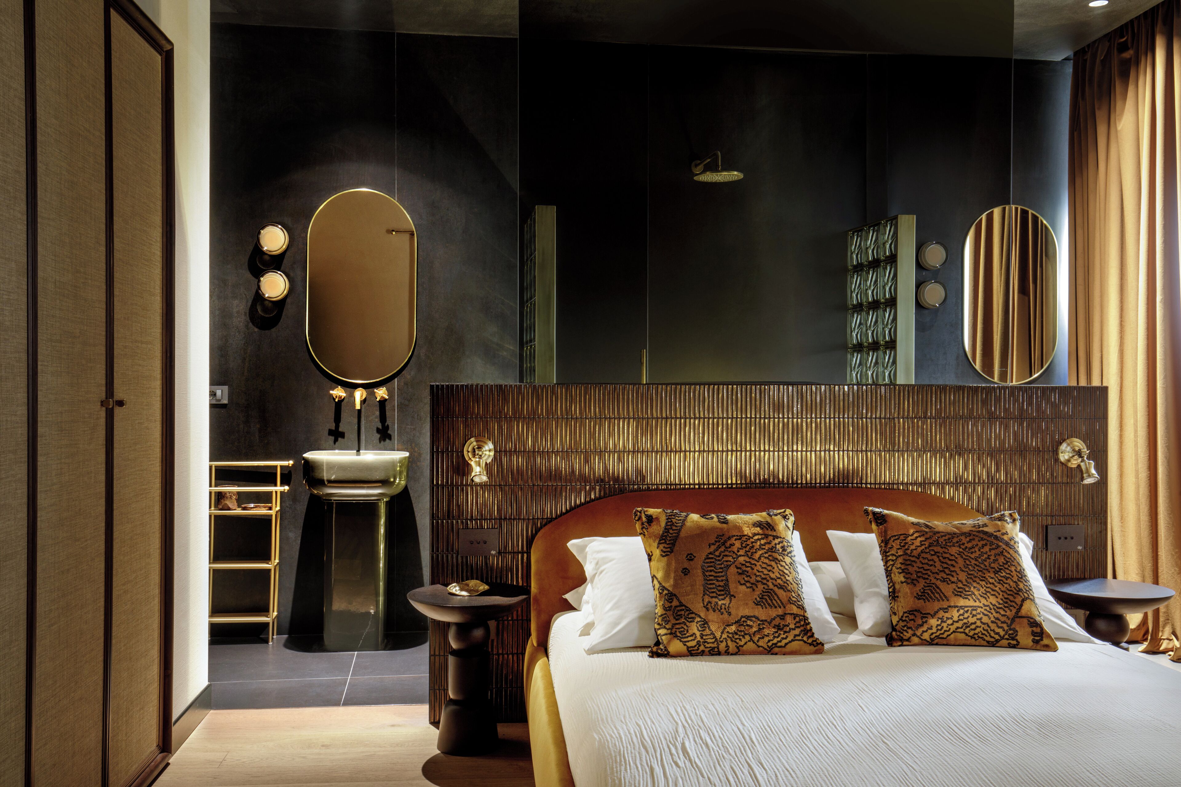 A modern hotel room with a large bed, a vanity with a mirror, and a small bathroom.