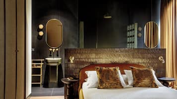 A modern hotel room with a large bed, a vanity with a mirror, and a small bathroom.