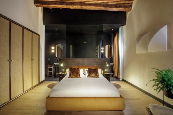 A modern bedroom with a large bed, wooden flooring, and a minimalist design. - Palazzo Serpe Suites near Colosseum (Rome)