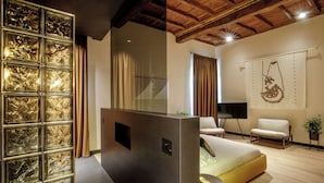A modern living room with a sofa, a television, and a decorative wall panel. - Palazzo Serpe Suites near Colosseum (Rome)