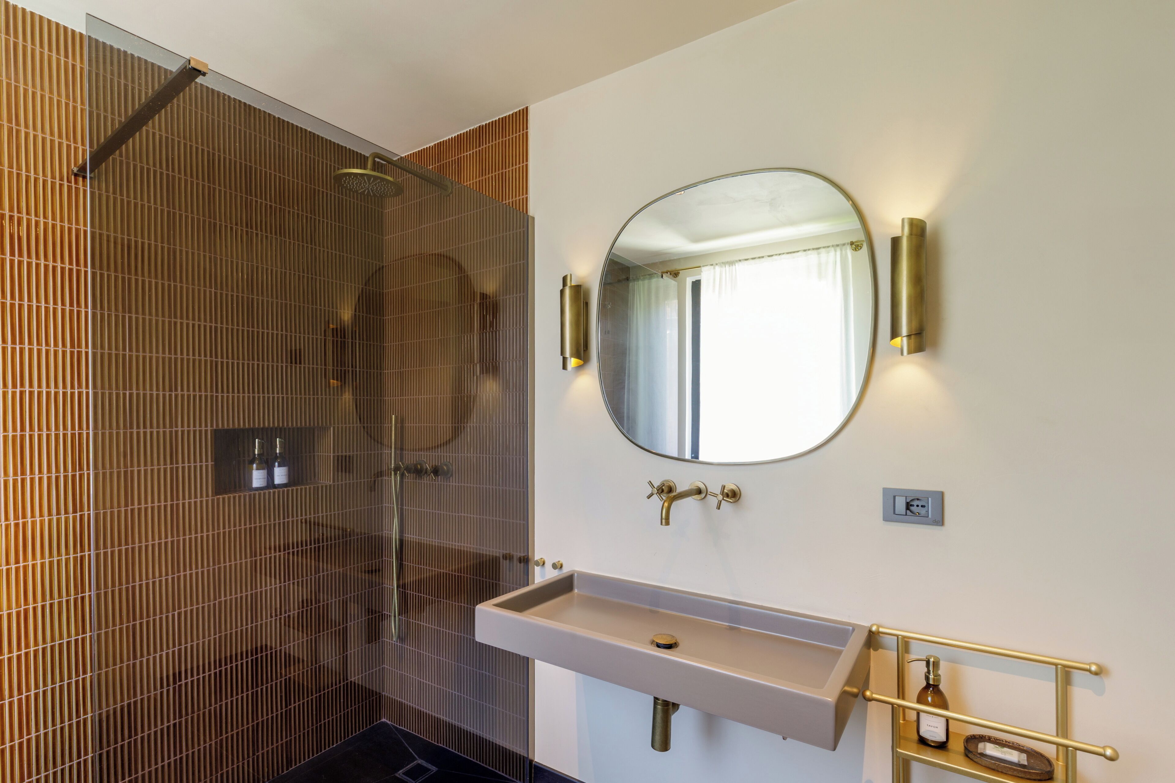 A bathroom with a shower, a sink, a mirror, and a towel rack.