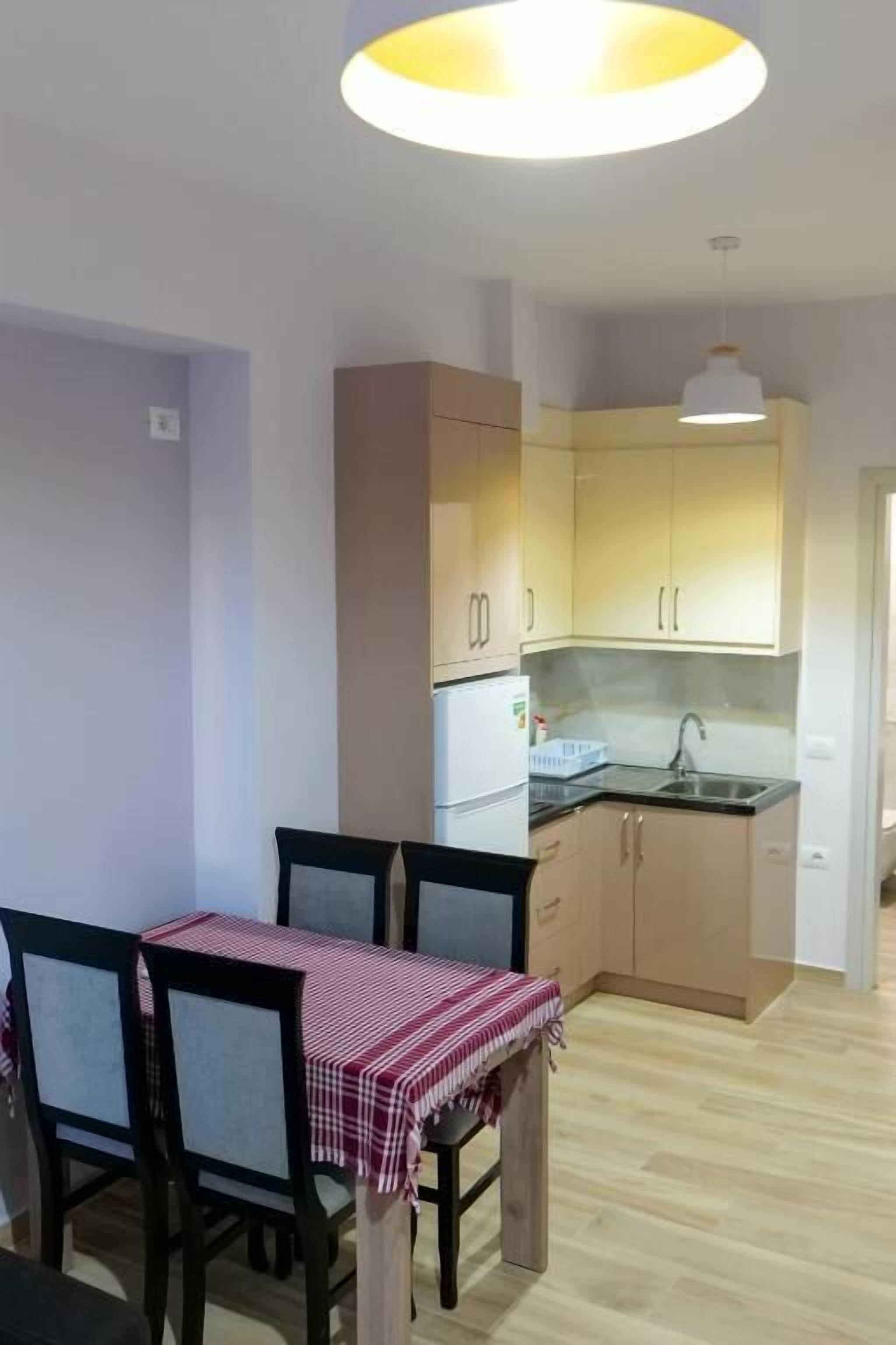 A compact kitchen with light wood cabinets, a sink, and a refrigerator.