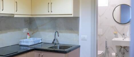 A compact kitchen with a sink, cabinets, and a countertop.