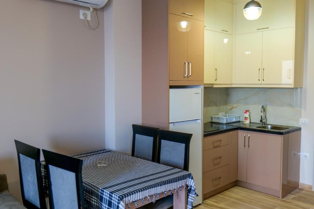 A compact kitchen with a dining table, chairs, and a refrigerator.
