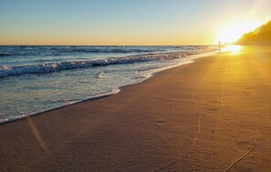 Ein Strand mit Wellen und einem Sonnenuntergang.