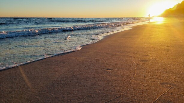Een strand met golven en een zonsondergang.
