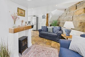 Relax in this inviting living area with a sofa, armchair, and wood-burning stove.