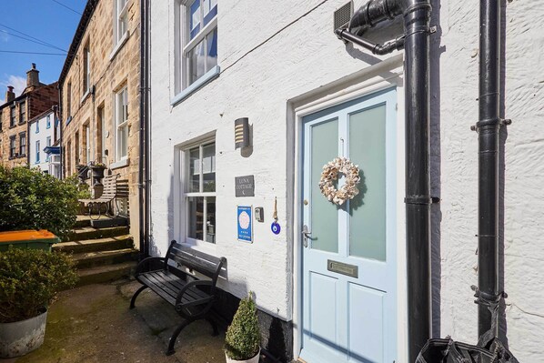 Charming cottage with a traditional design, featuring a small porch and a blue door.