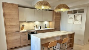 Cozinha moderna com armários de madeira, uma ilha central com banquetas e luminárias de vime suspensas.