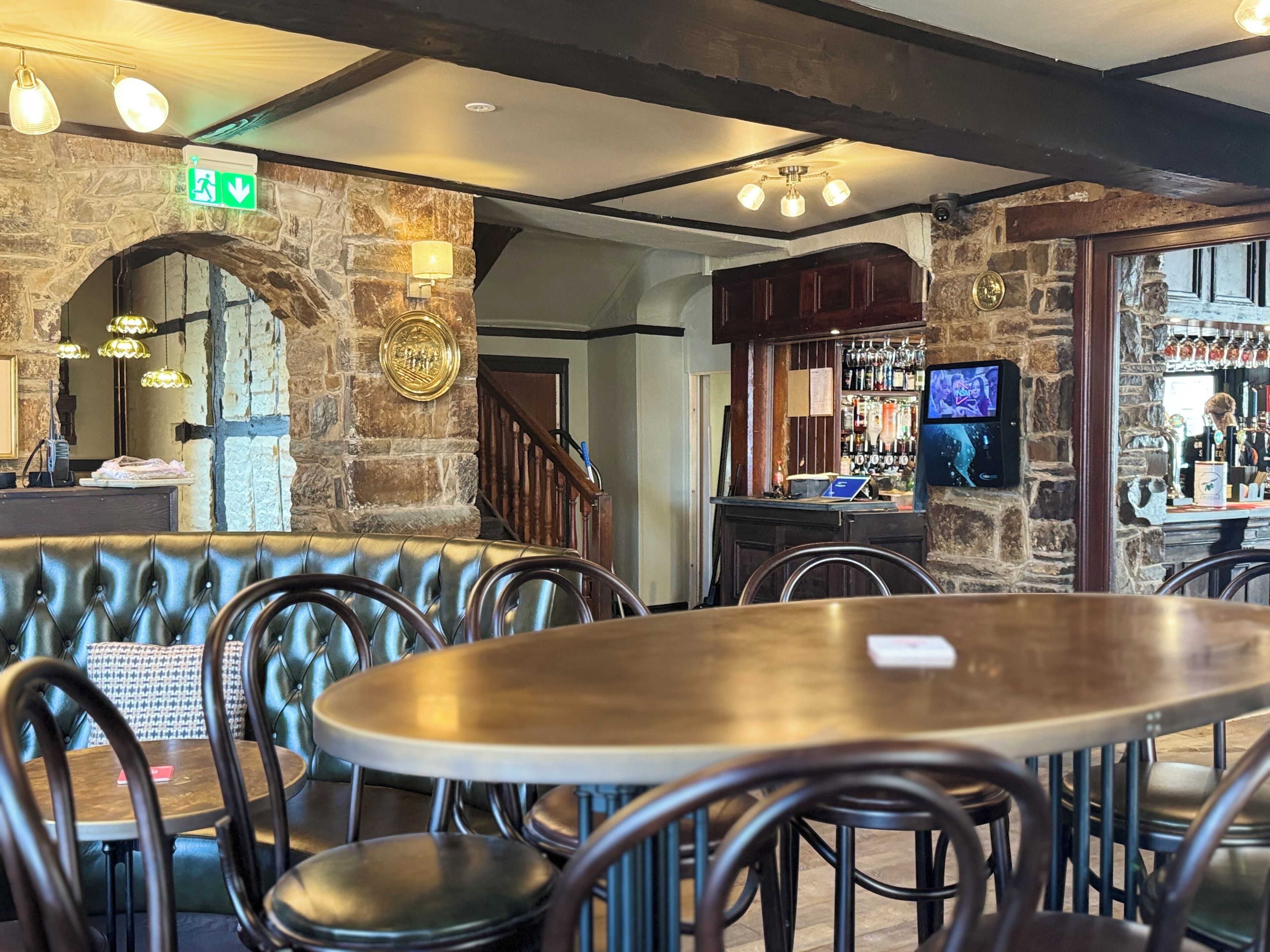 A restaurant with stone walls, leather booths, and a bar area with a TV.