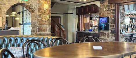 A restaurant with stone walls, leather booths, and a bar area with a TV.