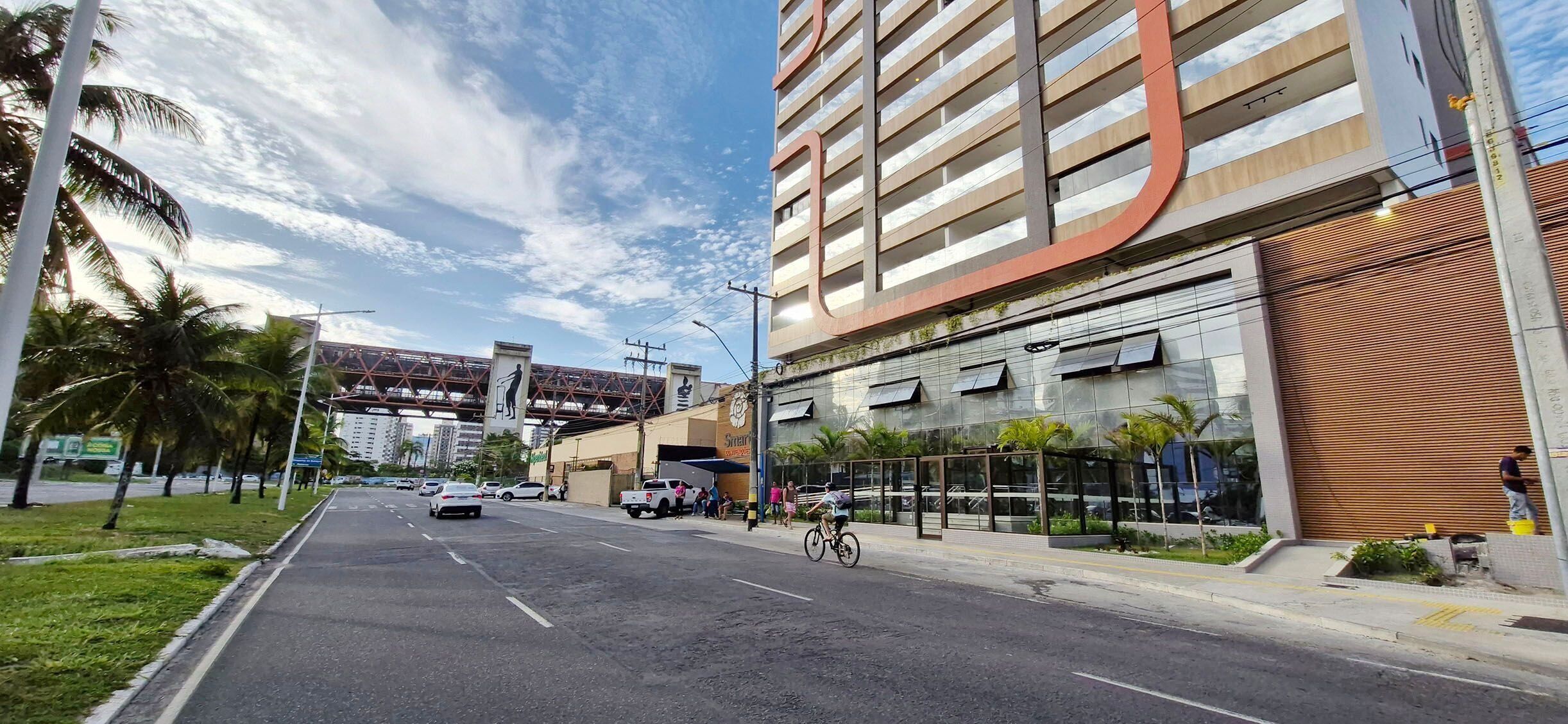 A modern building with a glass facade, a covered entrance, and a pedestrian walkway.