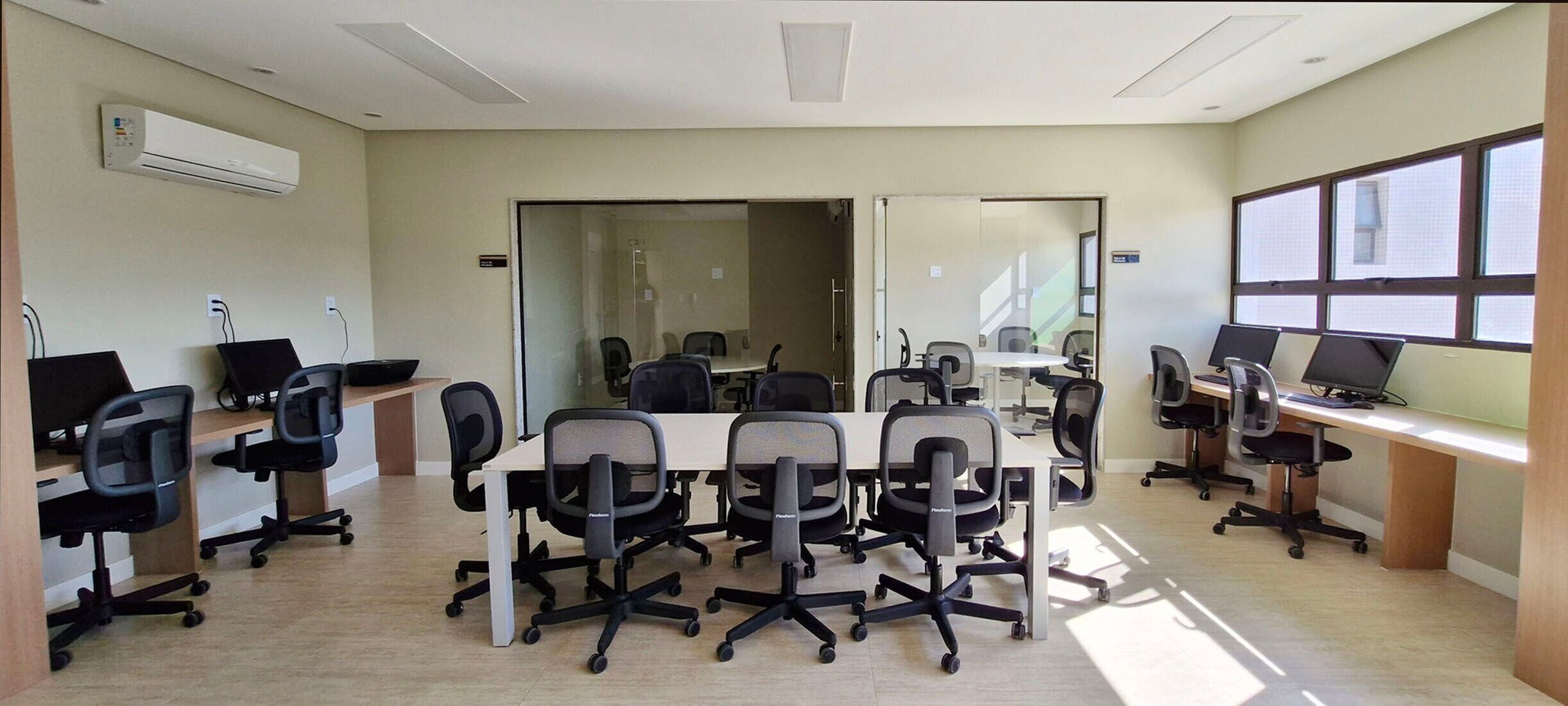 A conference room with a large table, multiple chairs, and computer monitors.