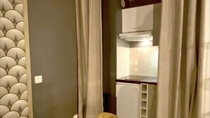 A room with a patterned wall, a yellow chair, and a kitchen area visible through a doorway. - Apartment in Biarritz (Biarritz)