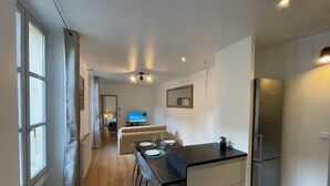 A modern kitchen with a dining area, a refrigerator, and a television in the background. - Les M Riers in Grenoble (Grenoble)