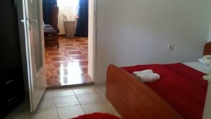 A bedroom with a wooden bed, a red rug, and a white towel on the bed. - Apartments Štrbić (Gornji Karin)
