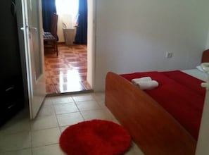 A bedroom with a wooden bed, a red rug, and a white towel on the bed. - Apartments Štrbić (Gornji Karin)