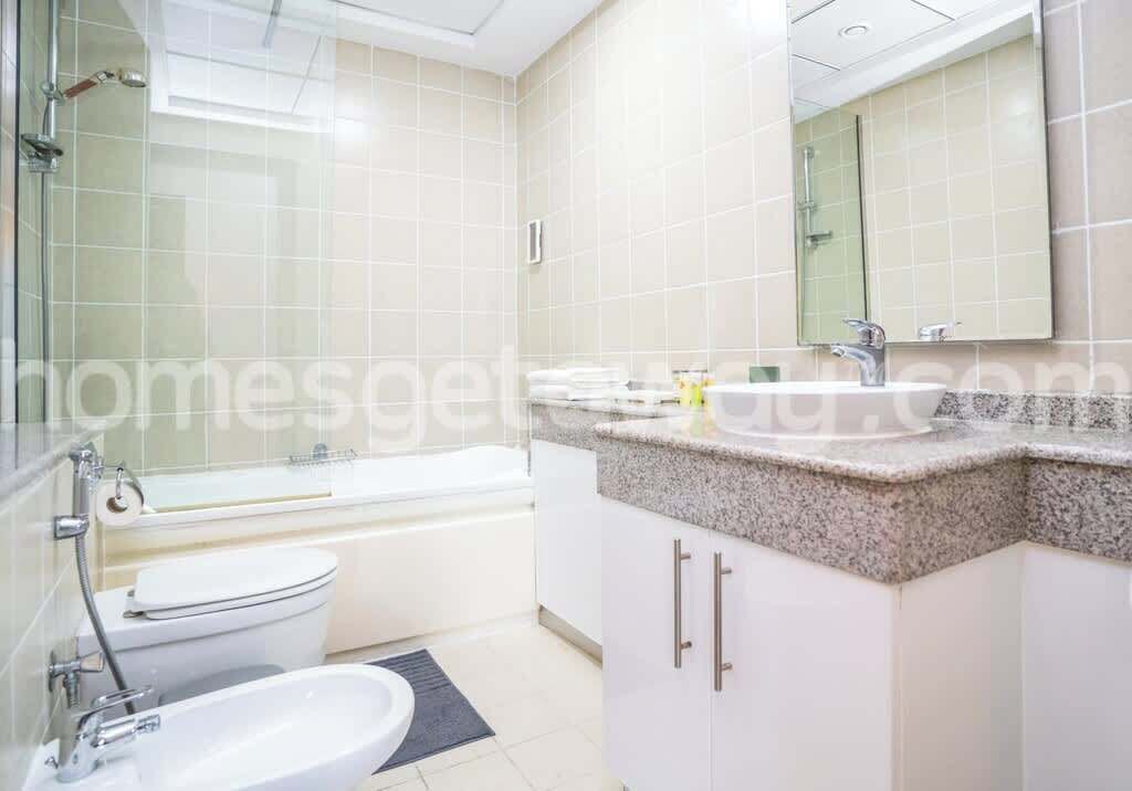 A bathroom with a toilet, bidet, sink, and a large mirror.
