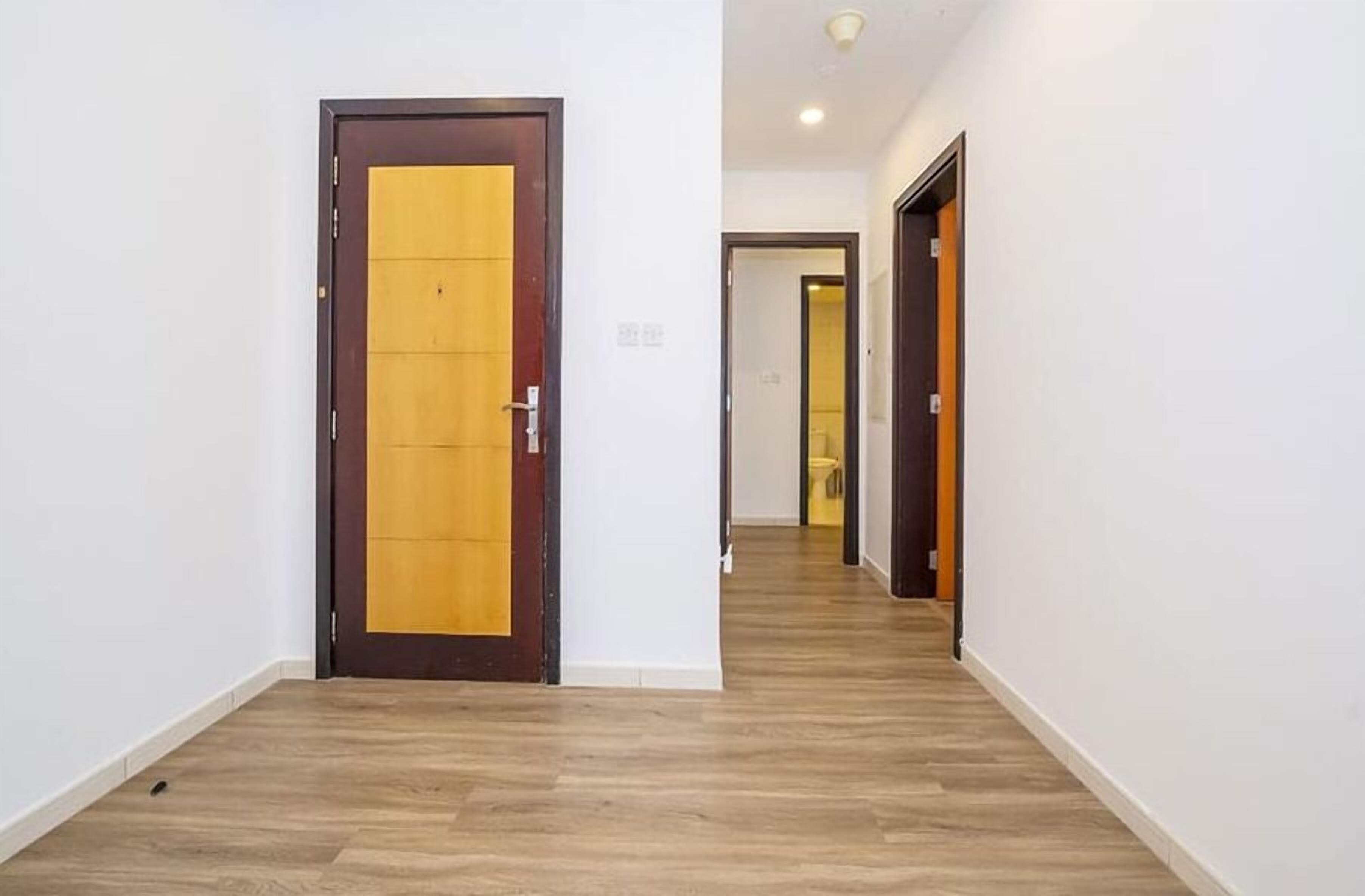 A hallway with wooden flooring and a door with a yellow panel.