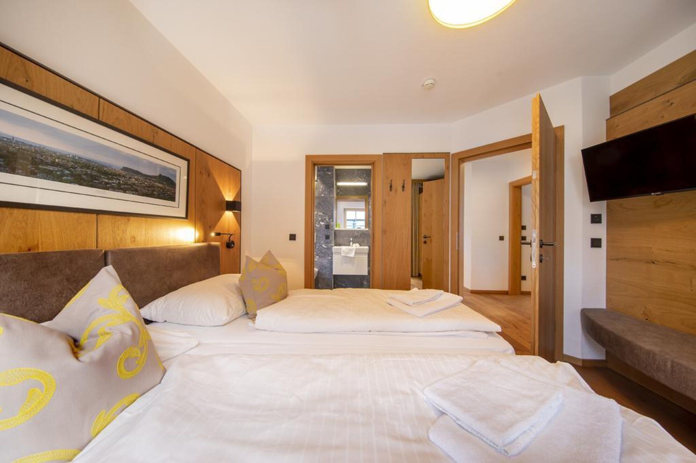 Ein Hotelzimmer mit einem großen Bett, einem an der Wand montierten Fernseher und einem hölzernen Kopfteil.