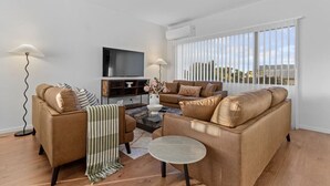 A modern living room with a sofa set, a coffee table, and a flat-screen TV. - ﻿Premium Sunset Townhouse | 6 Aircons near Airport (Auckland South)