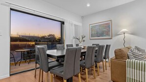 A dining area with a table and chairs, a sofa, a lamp, and a painting on the wall. - ﻿Premium Sunset Townhouse | 6 Aircons near Airport (Auckland South)