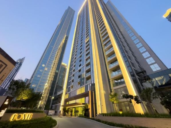 A high-rise building with multiple floors, large windows, and a well-lit entrance area.