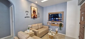 Relax in this stylish living room with a sofa, flat-screen TV, and decorative shelf.