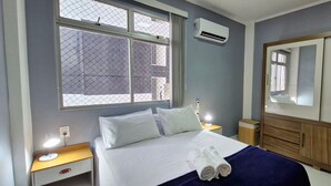 Ein Hotelzimmer mit Bett, Nachttisch, Spiegel und Fenster mit Ausblick.