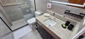 Enjoy a refreshing shower with a clear view of the bathroom area, featuring a sleek shower, sink, and soap dispenser.