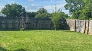 A backyard with a wooden fence, a lawn, and a tree. - Newly renovated, spacious, modern home near Hospitals and LSU. (Baton Rouge)