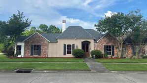 A two-story house with a brick facade, a central entrance with a door, and a chimney. - Newly renovated, spacious, modern home near Hospitals and LSU. (Baton Rouge)