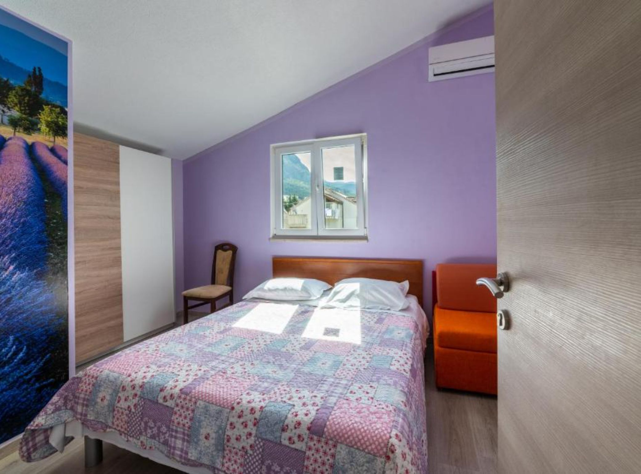 Une chambre à coucher comprenant un lit, une chaise, une fenêtre et un appareil de climatisation.