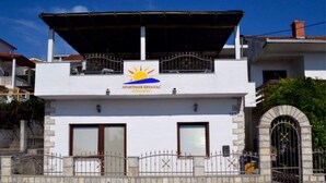 A two-story building with a sign reading "APARTMANI KRIVAC" and a sun symbol. - Apartments Krvavac (Slivno)