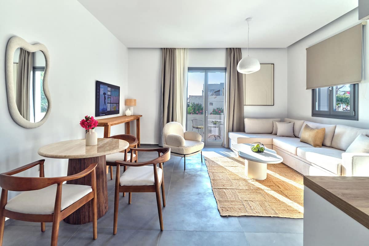A modern living room with a sofa, dining table, chairs, and a large window.