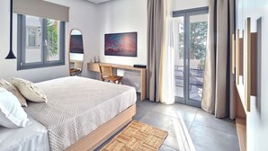 A modern bedroom with a large bed, a desk, and a view of the outdoors. - Parousia Luxury Apartments (Paros)