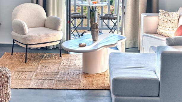 A modern living room with a view of the sea, a round coffee table, and two sofas. - Parousia Luxury Apartments (Paros)